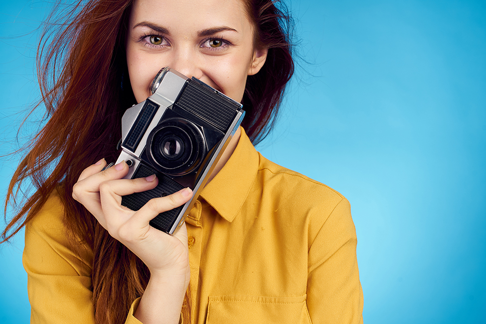 portrait photography female camera yellow top blue background smiling